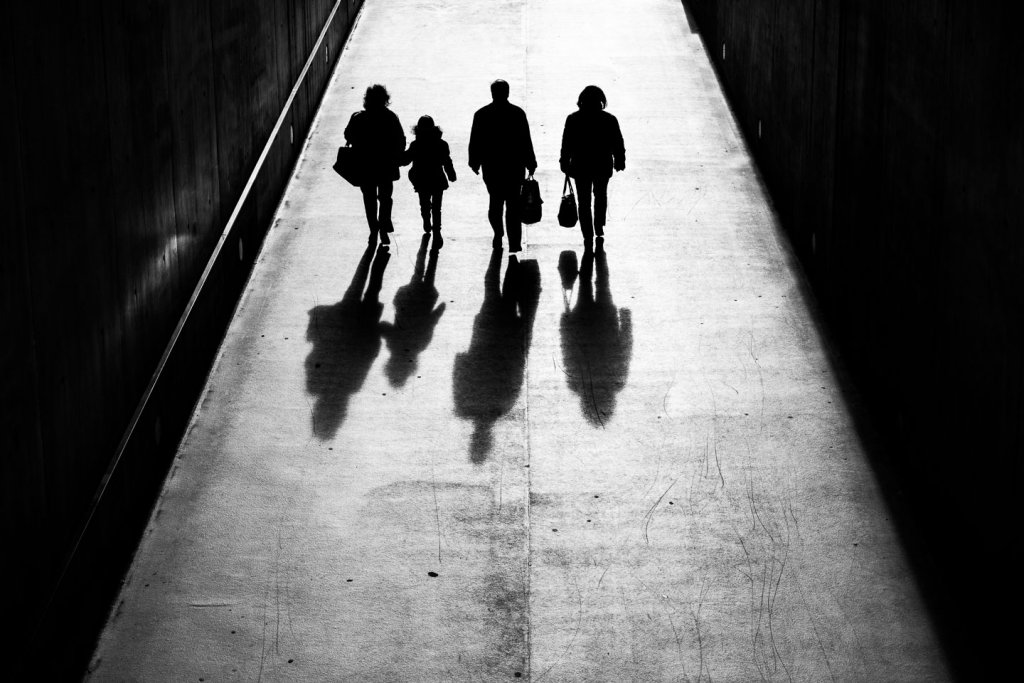 Der entscheidende Moment in der Schnappschussfotografie Silhouetten von vier Personen mit langen Schatten in einer Unterführung