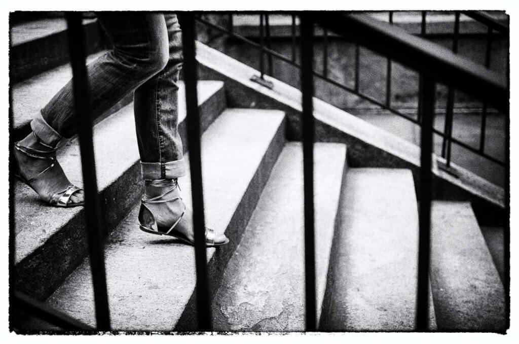 Linienführung auf einer Treppe als Schwarzweissmotiv. Person steigt eine Treppe hinauf. Geländer und Stufen bilden starke Linien in der Schwarzweissfotografie.