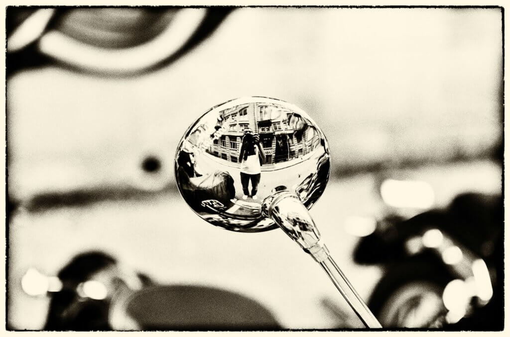 Spiegelung im Motorrad-Rückspiegel mit Sepia-Tonung. Selbstporträt in einem Motorrad-Rückspiegel mit Sepia-Effekt.