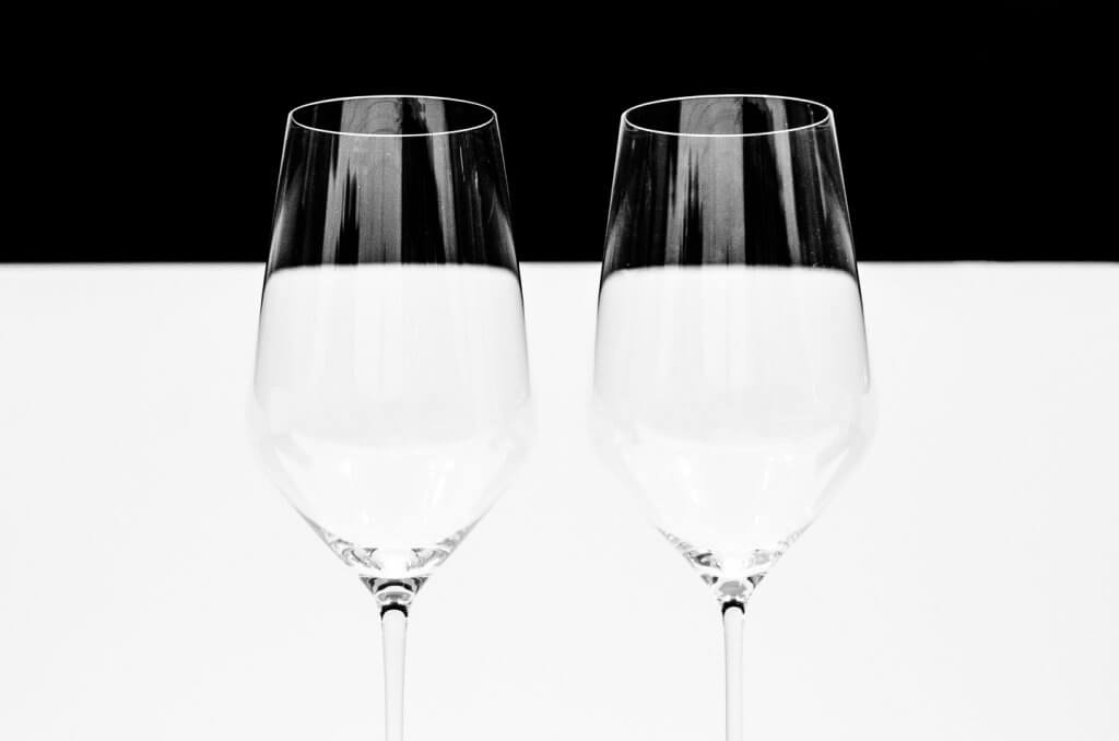 Minimalistische Weingläser in Schwarzweiss Schwarzweissfoto von zwei Weingläsern vor einem schwarzen Hintergrund mit minimalistischer Bildgestaltung.